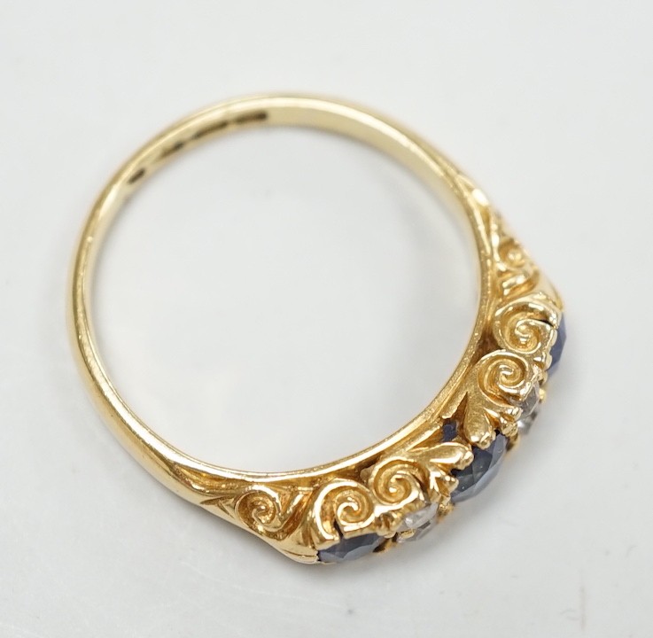 A late Victorian 18ct gold and three stone sapphire set ring, with four stone diamond set spacers, size M, gross weight 4.1 grams.
